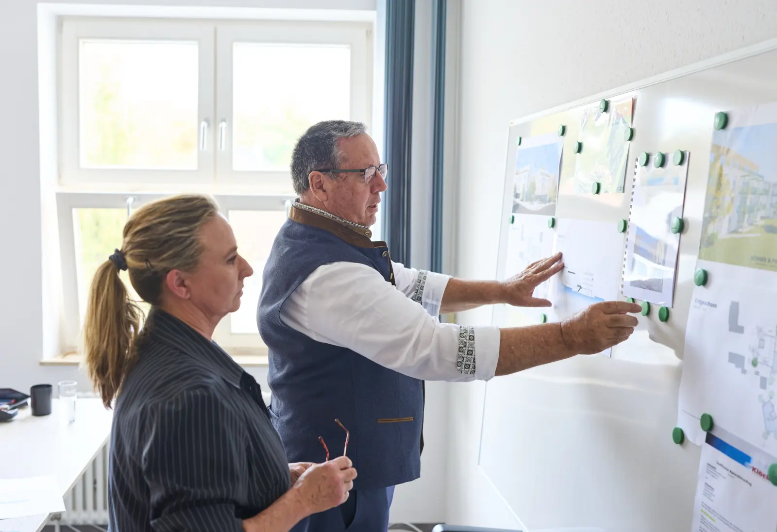 Wolfgang Klöck und Barbara Ammon besprechen Pläne an der Projekttafel im Büro